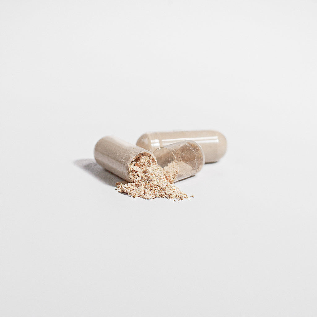 Two open capsules with a powdery substance on a light gray background