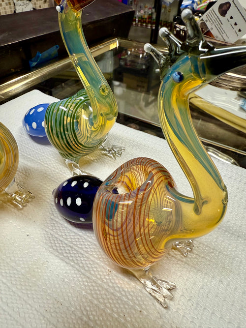  Ripkitty 5" peacock glass pipe — side profile showing full peacock form with teal-striped body, amber beak mouthpiece with crest prongs, and blue dot bowl