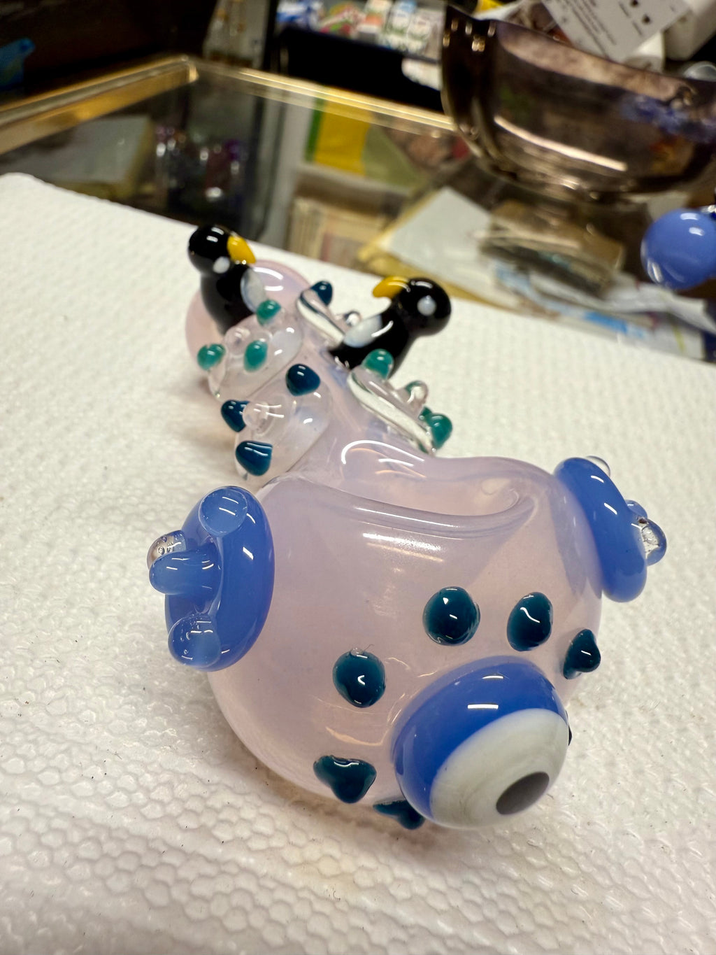 Top-down view of Ripkitty penguin art spoon pipe — pink with penguin figures and blue dot pattern visible from above